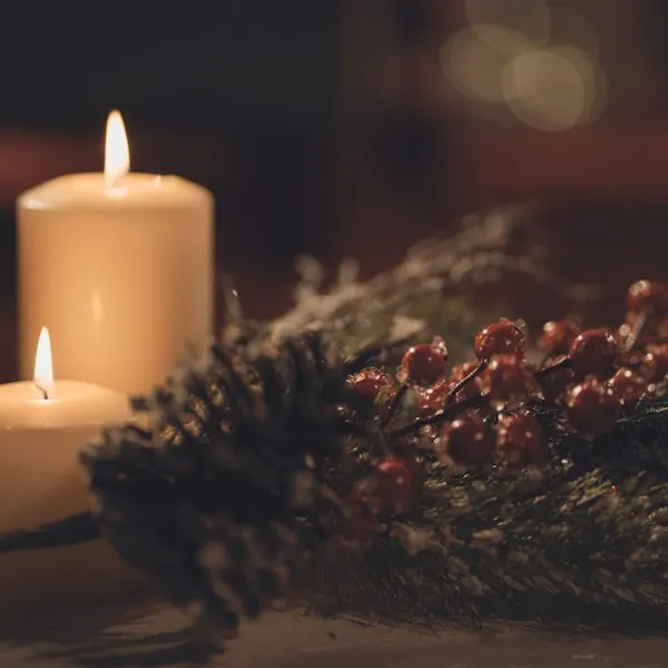 Cream pillar candles beside pine and berries