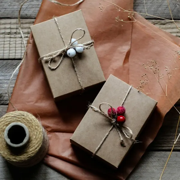 Two presents in brown paper and twine on a wooden table