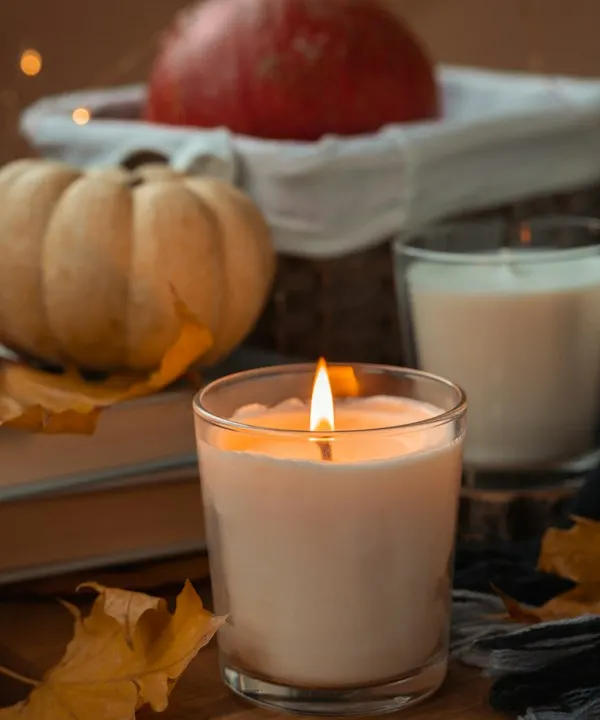 A white pillar candle burning in a clear glass holder