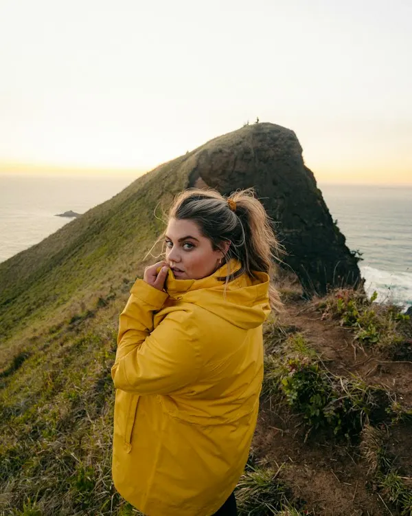 A woman in a yellow rain shell on a clifftop by the sea
