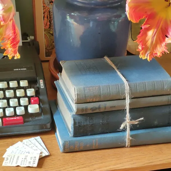 A stack of old books tied with string beside a typewriter