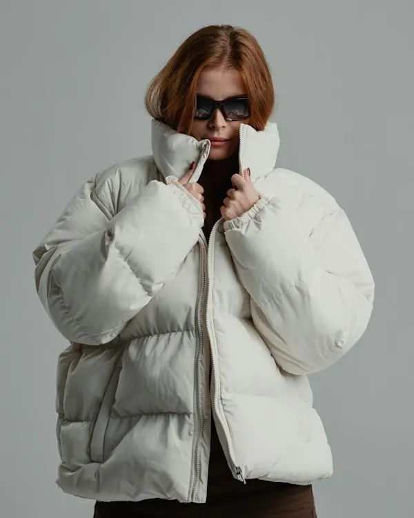 A woman in a white down jacket and sunglasses