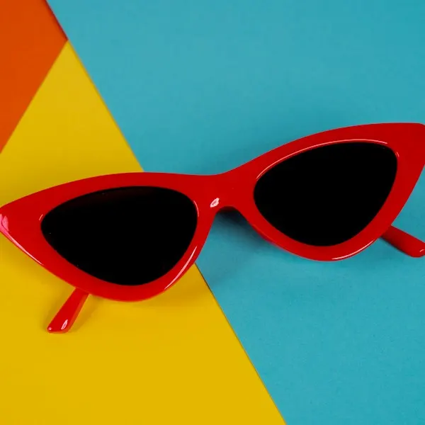 Red cat-eye sunglasses on a blue and yellow background