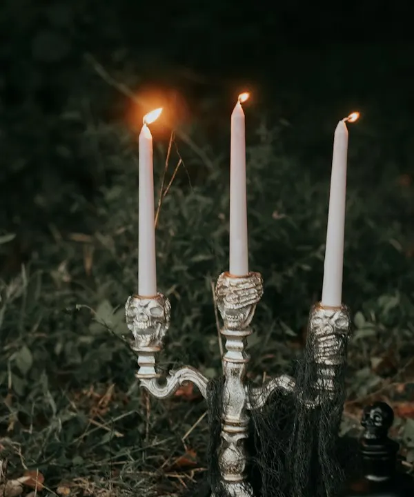 Tall white taper candles in vintage holders on grass