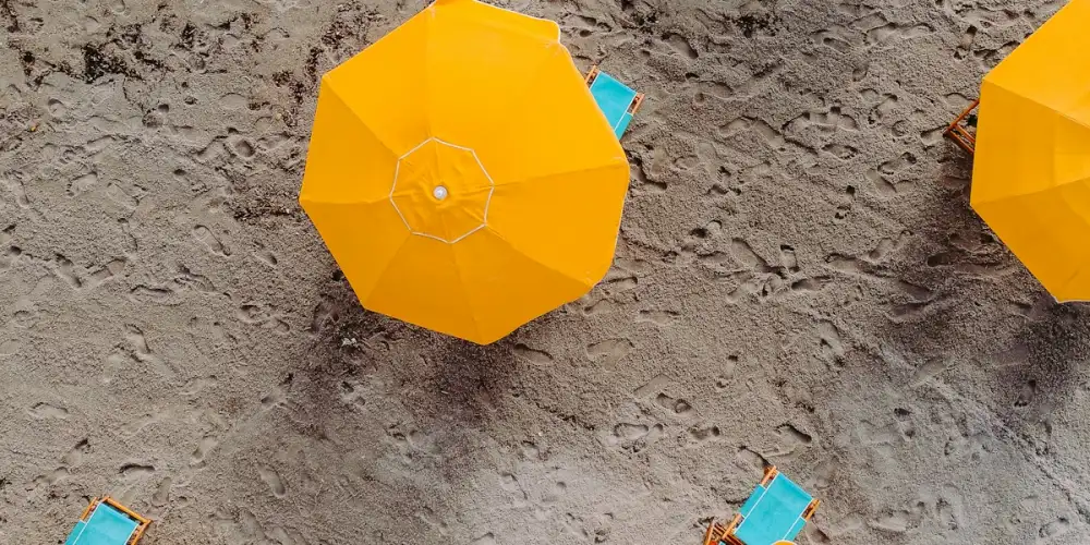 Yellow beach umbrellas on the sand, seen from above
